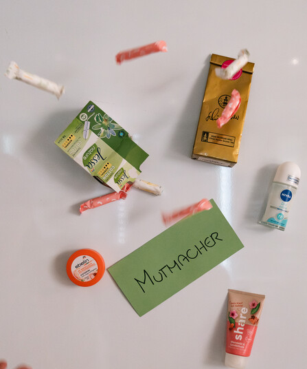 Tampons, Tees, Deo, Handcreme und eine Lippenpflege fliegen durch das Bild.