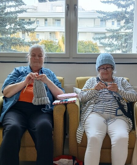 Zwei Senior*innen sitzen nebeneinander und häkeln für die füreinand' Häkelaktion.