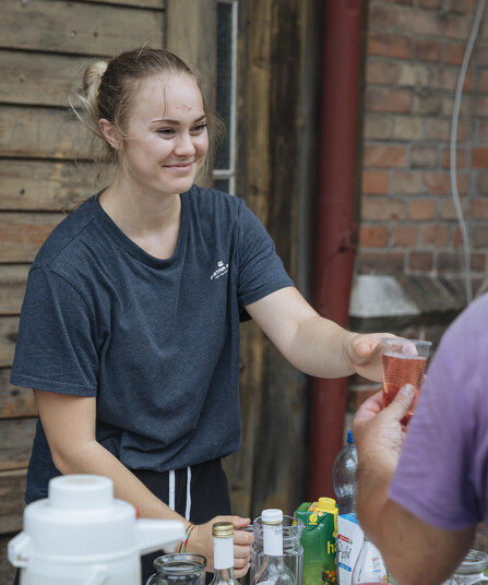 Eine junge Frau verteilt Getränke an Menschen.